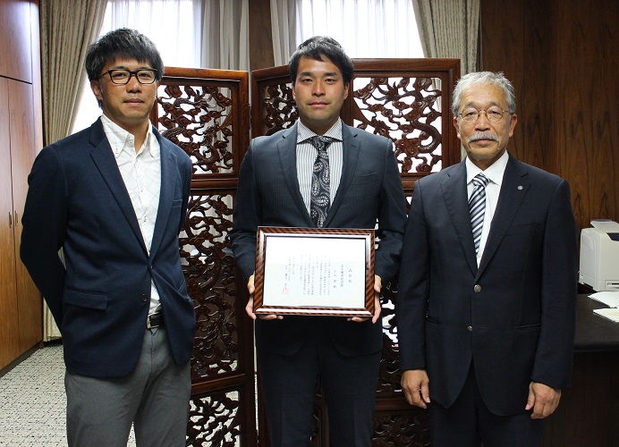 学長報告の様子。左から指導教員の髙井洋平准教授、小川さん、松下学長