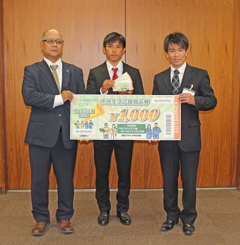 11月4日交付式の様子（左から） 前阪茂樹学生支援担当学長補佐、太田さん、坂野市長公室長